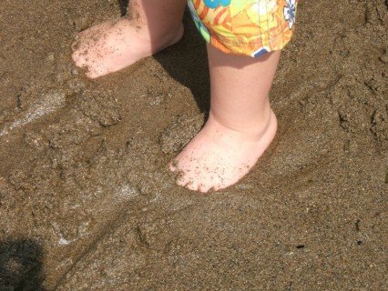 Baby Feet Buried In The Beach Sand